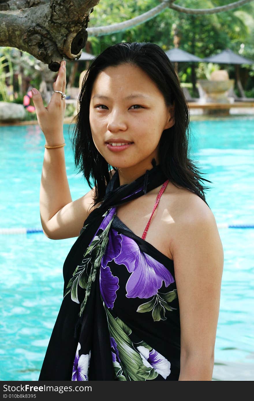 Asian woman in a pretty summer sarong by the pool. Asian woman in a pretty summer sarong by the pool.