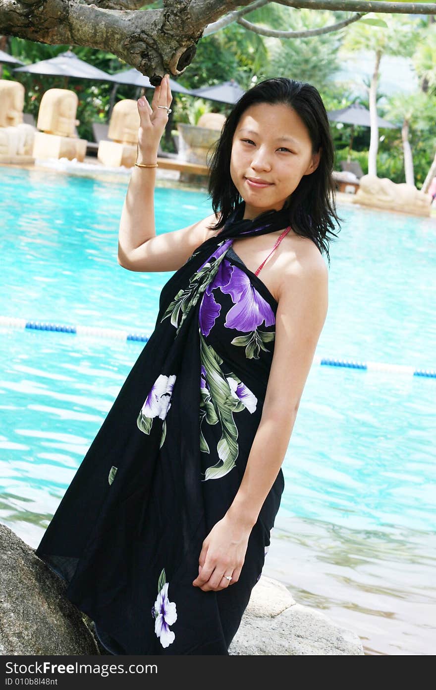 Asian woman in a pretty summer sarong by the pool. Asian woman in a pretty summer sarong by the pool.