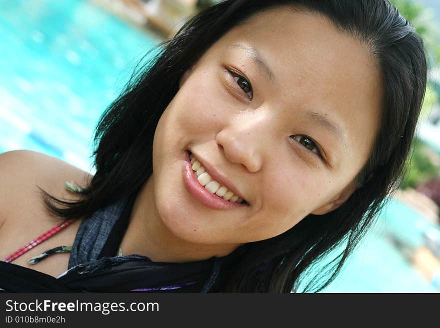 Asian woman in a pretty summer sarong by the pool. Asian woman in a pretty summer sarong by the pool.