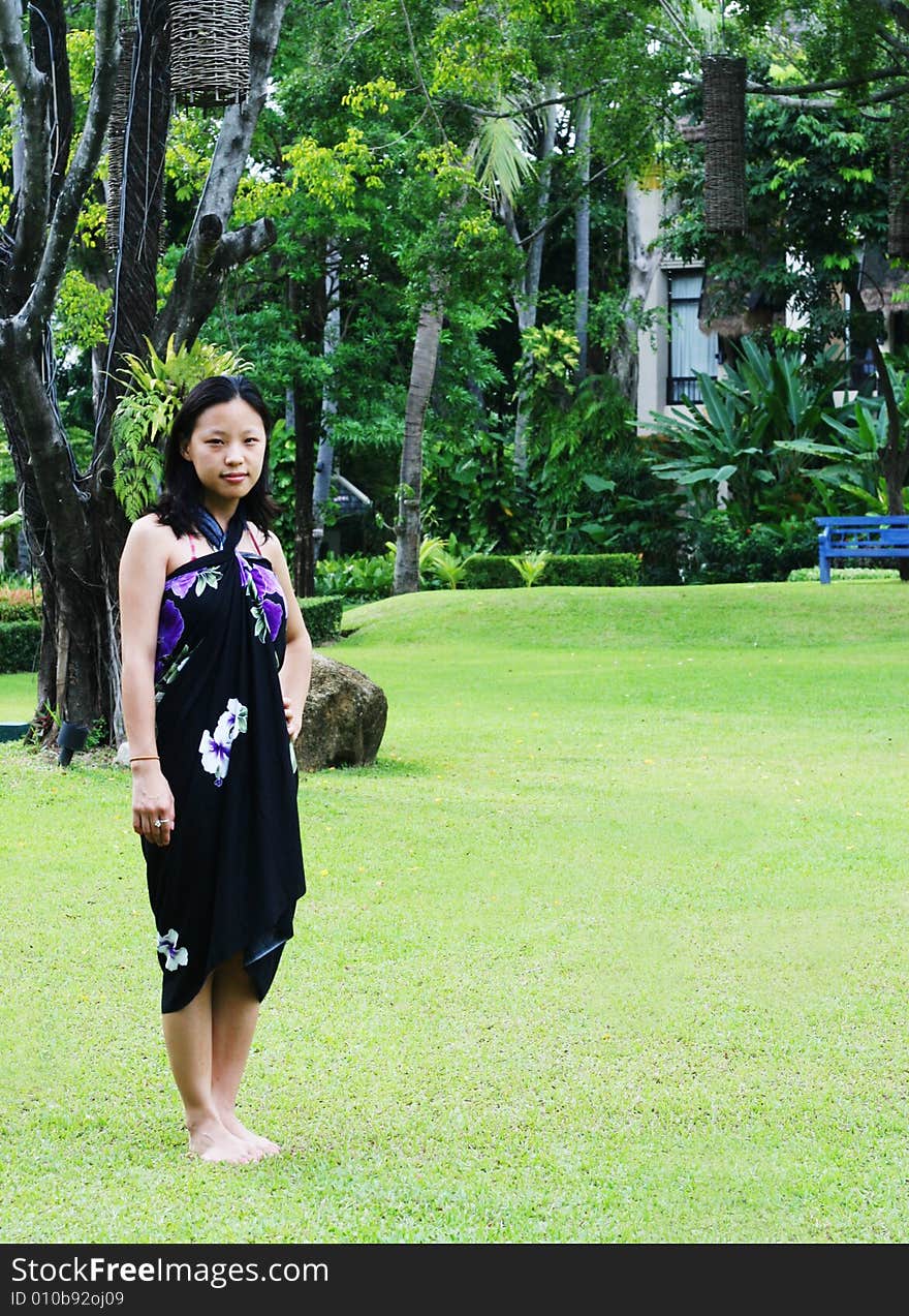 Asian woman in a pretty summer sarong looking at orchids. Asian woman in a pretty summer sarong looking at orchids.