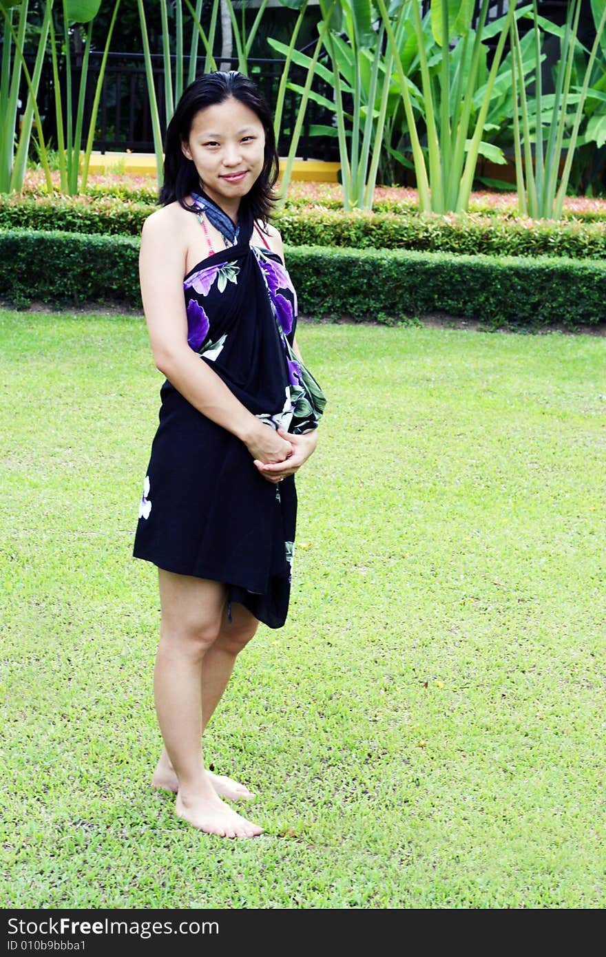 Asian woman in a pretty summer sarong in a tropical garden. Asian woman in a pretty summer sarong in a tropical garden.