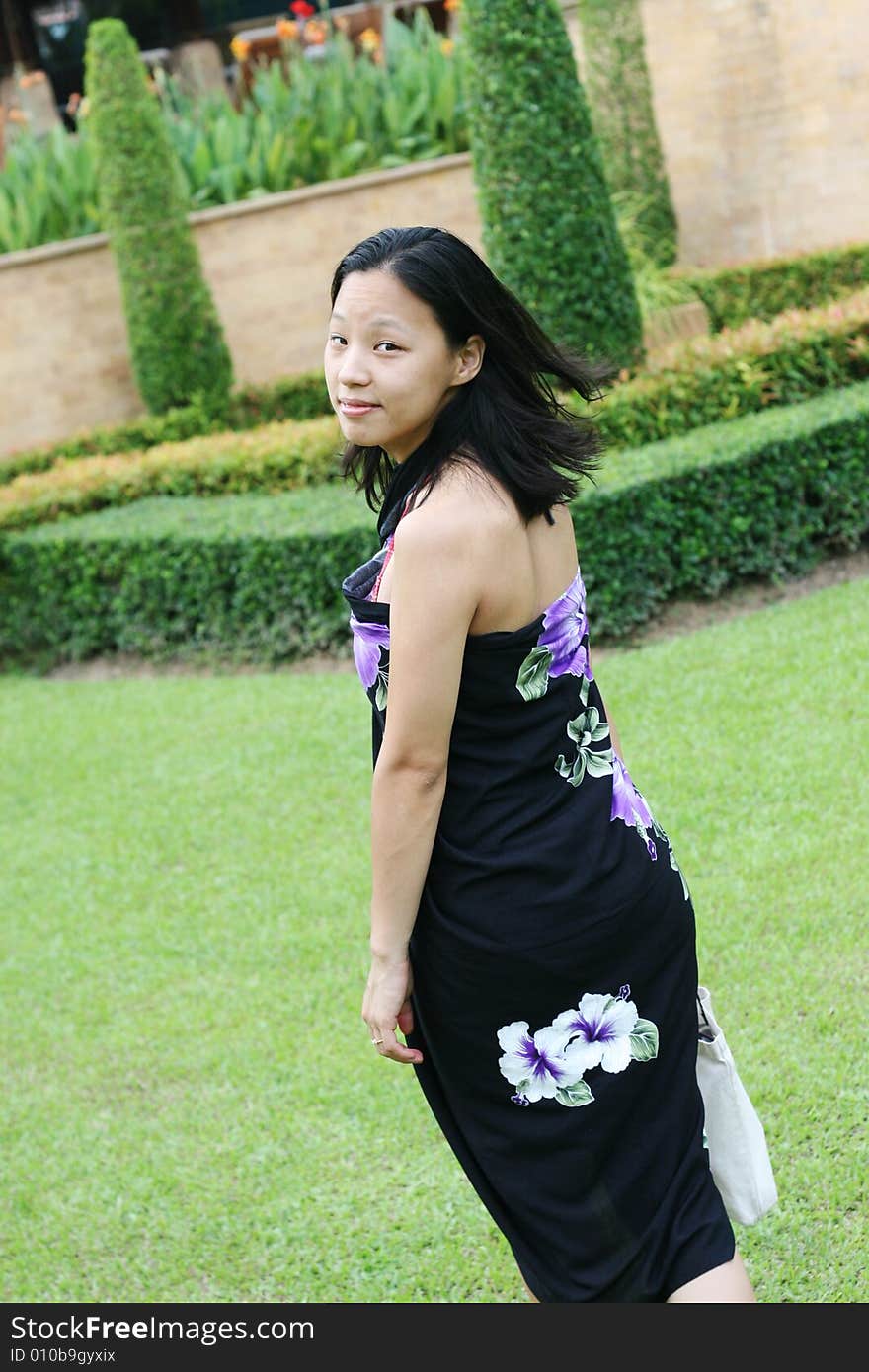 Asian woman in a pretty summer sarong in a tropical garden. Asian woman in a pretty summer sarong in a tropical garden.