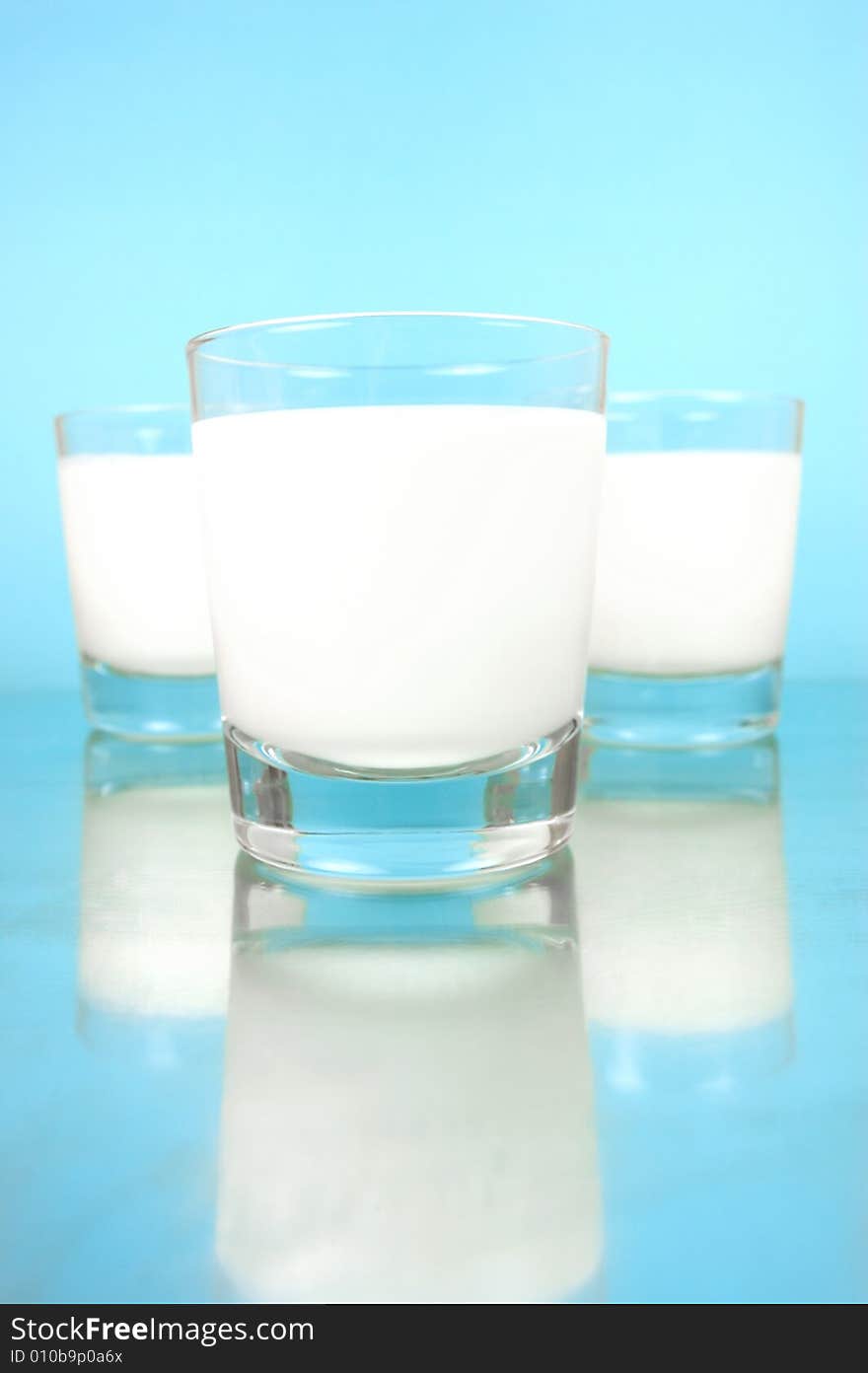 Glasses of milk isolated against a blue background. Glasses of milk isolated against a blue background