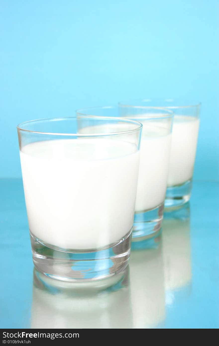 Glasses of milk isolated against a blue background. Glasses of milk isolated against a blue background