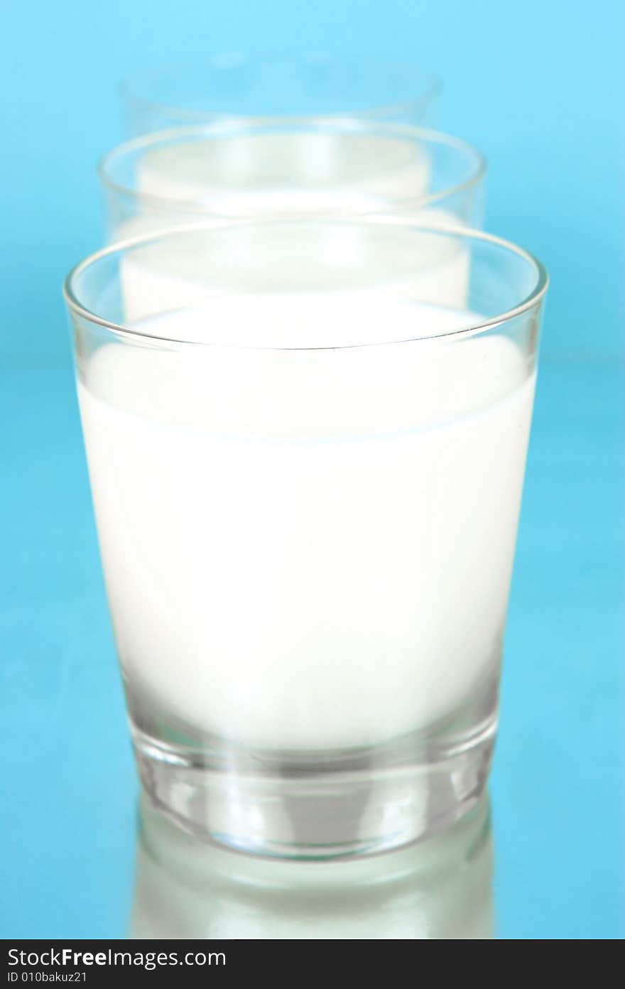 Glasses of milk isolated against a blue background. Glasses of milk isolated against a blue background