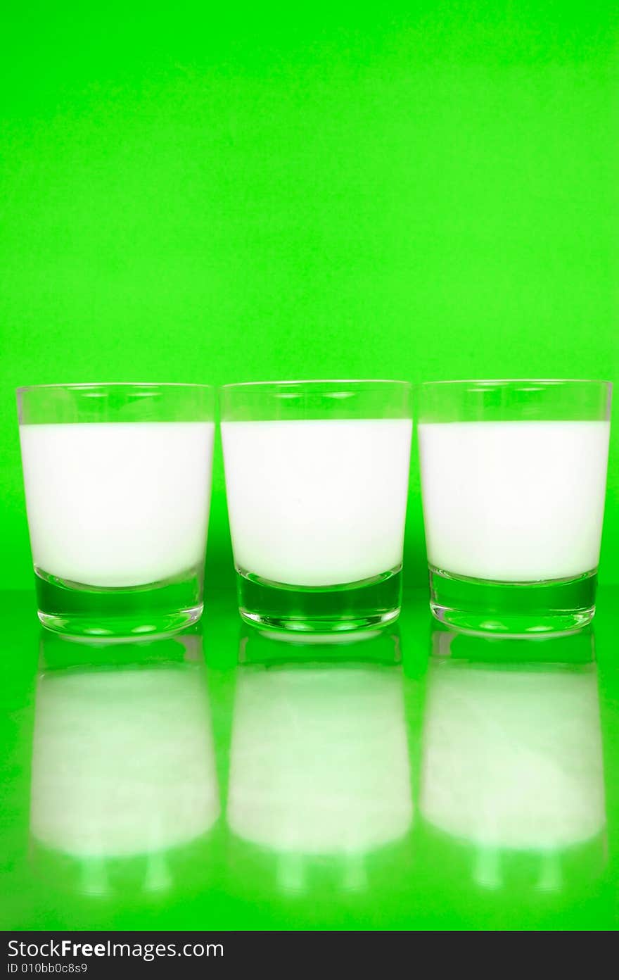 Glasses of milk isolated against a green background. Glasses of milk isolated against a green background