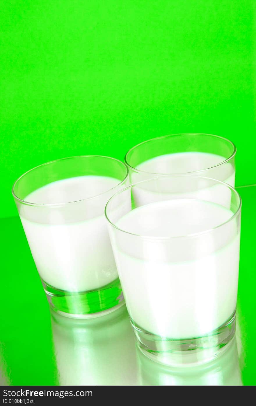 Glasses of milk isolated against a green background. Glasses of milk isolated against a green background