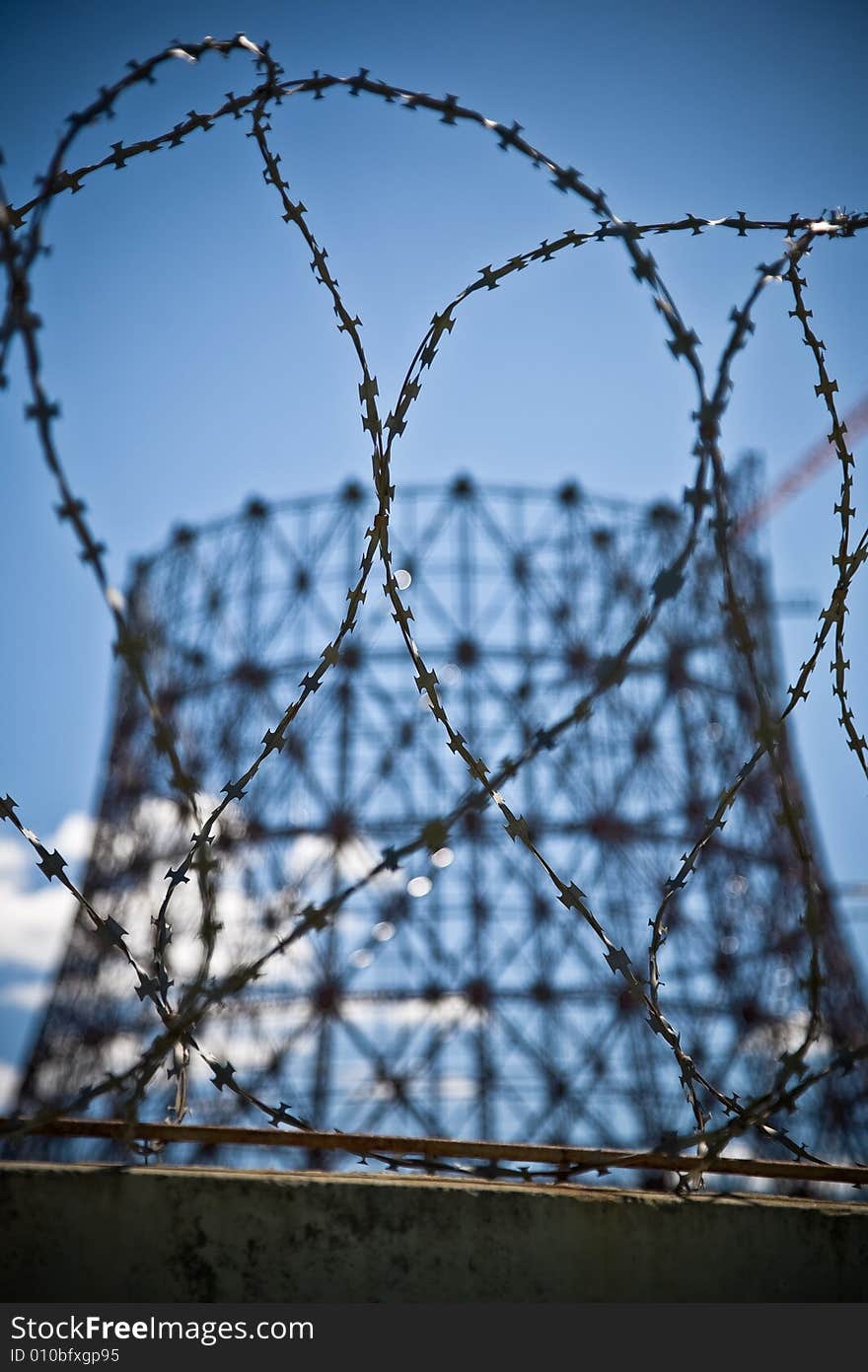 Construction of a power plant's cooling tower blurred against barb wire. Construction of a power plant's cooling tower blurred against barb wire