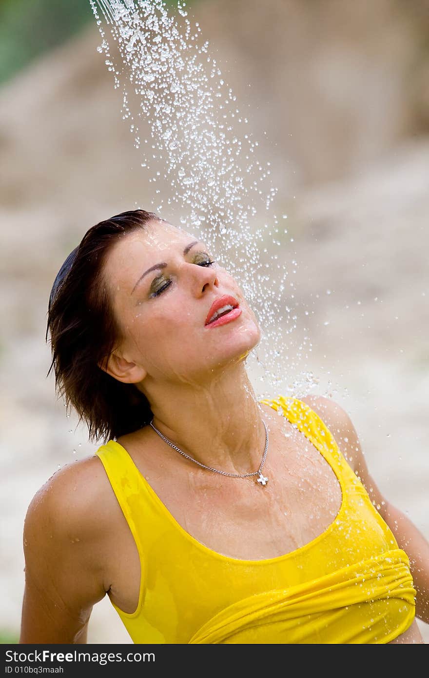 Beautiful girl relaxing under streaming and splashing water