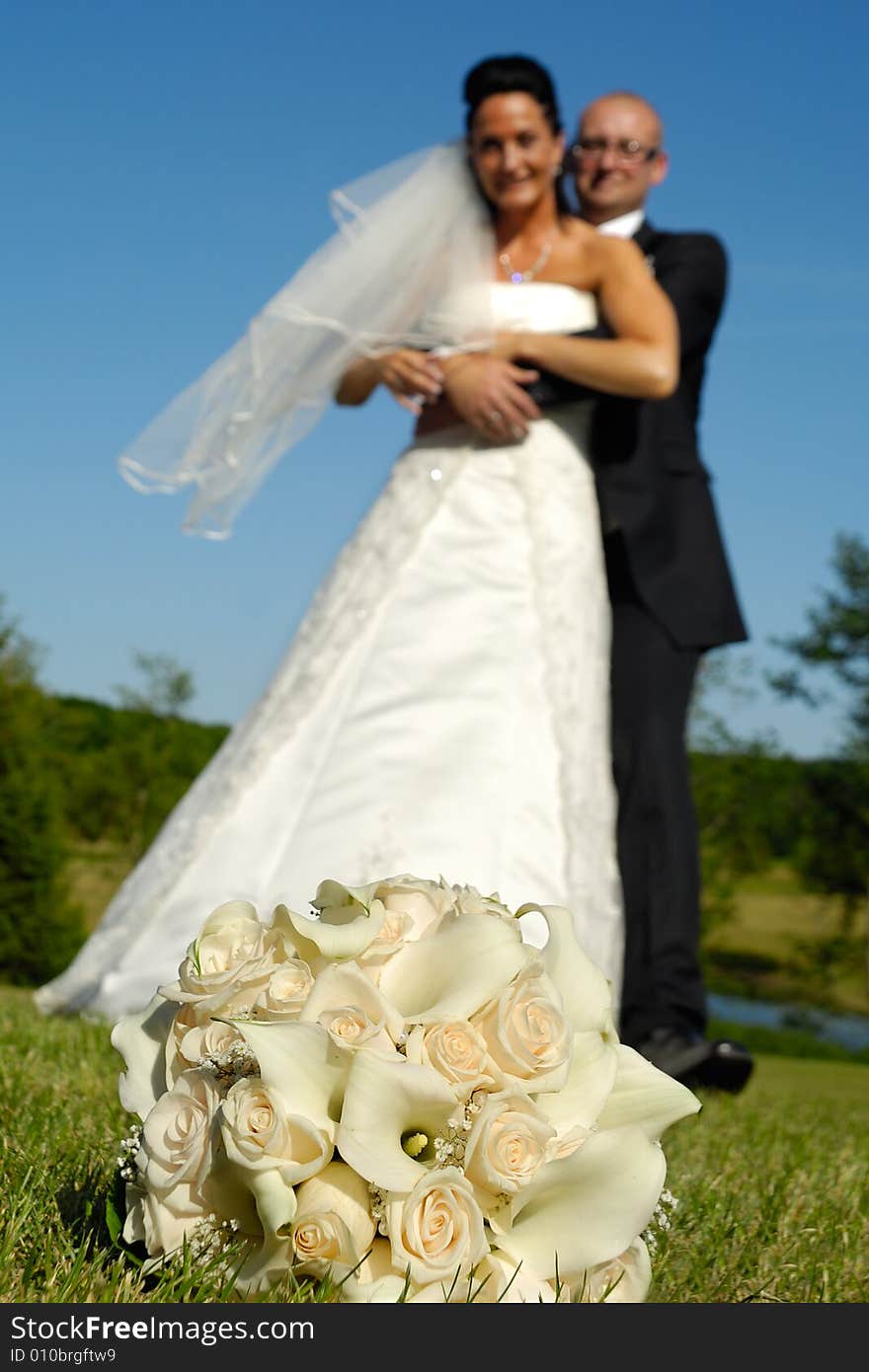 Wedding bouquet in focus and couple in blur. Wedding bouquet in focus and couple in blur