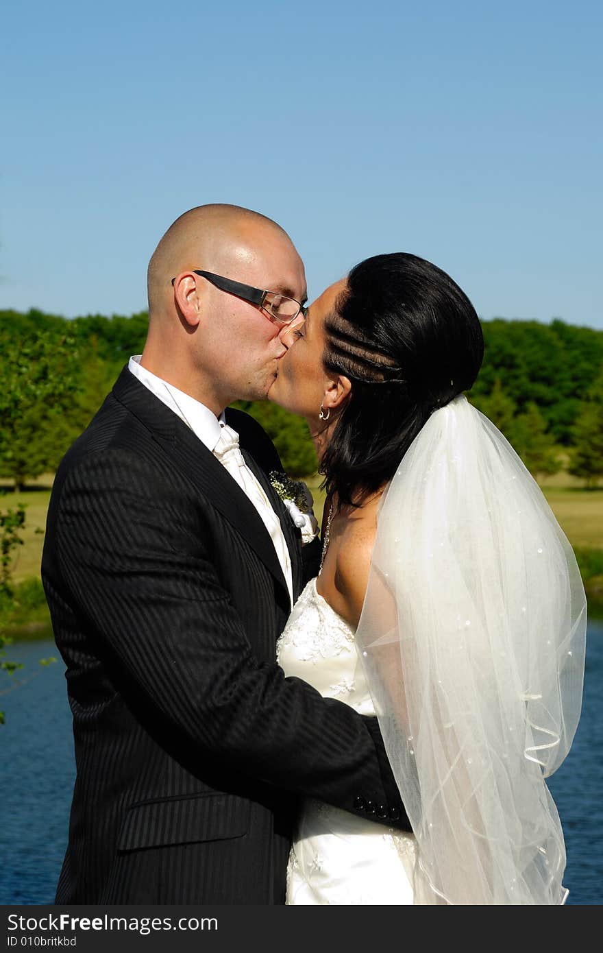 Bride and groom is kissing by the lake. Bride and groom is kissing by the lake.