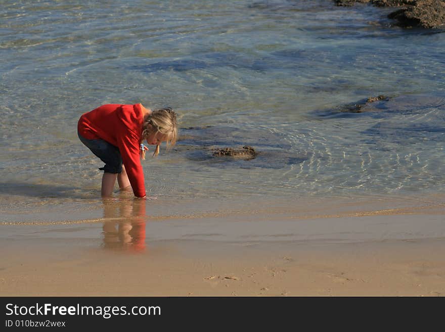 A beautiful white caucasian girl child playing in the water at the beach. A beautiful white caucasian girl child playing in the water at the beach