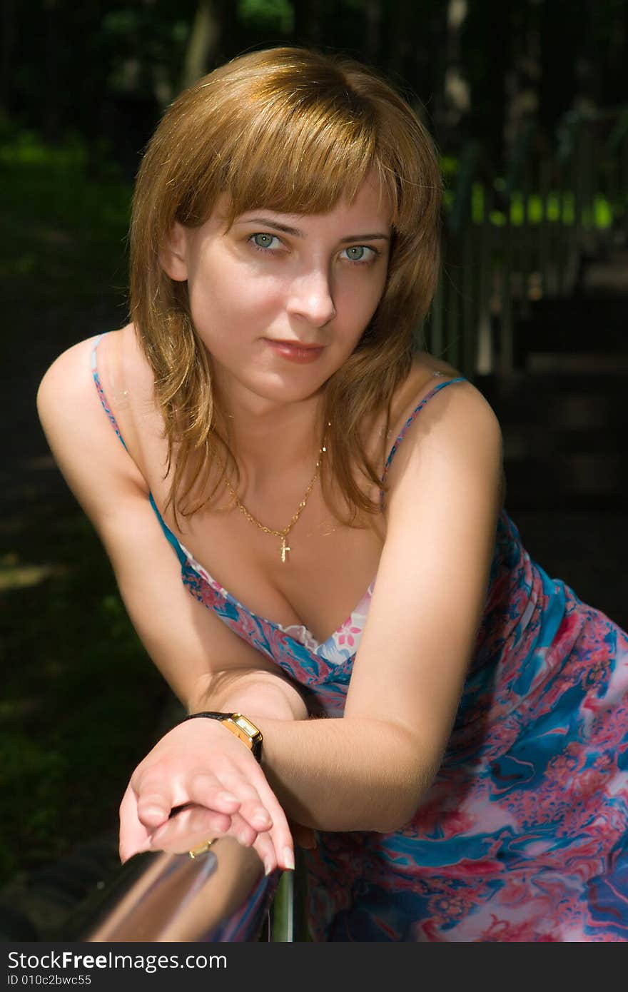 Beautiful girl stands having leaned on a steel handrail