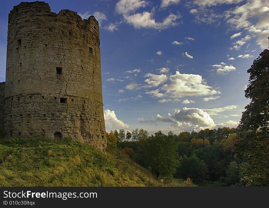 Medieval castle and green trees under blue sky with clouds. Medieval castle and green trees under blue sky with clouds