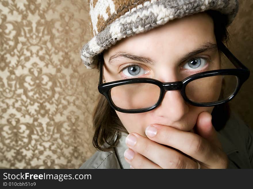 Closeup of Cute Nerdy Woman in a Knit Cap Covering Her Face With Her Hand