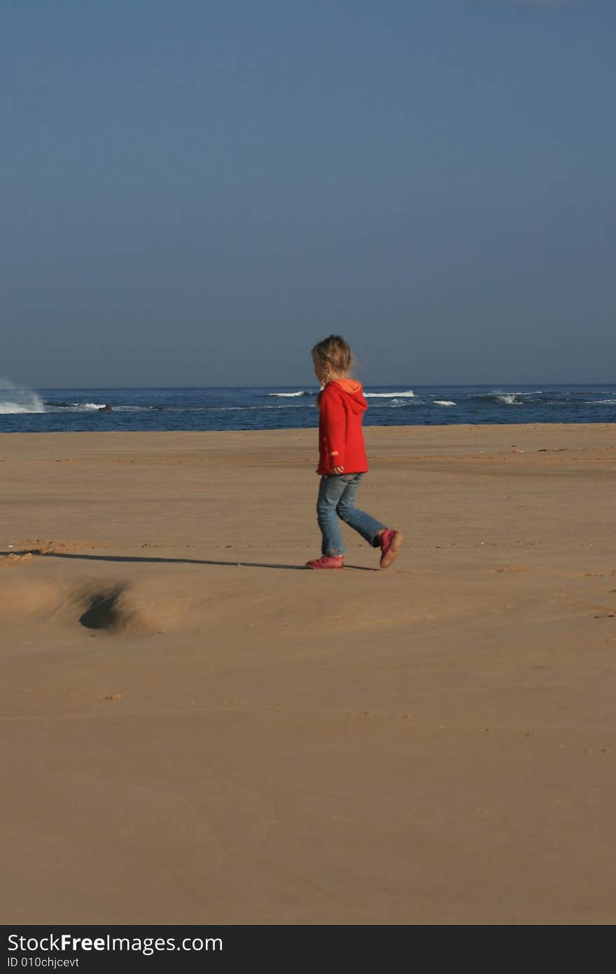 A white caucasian little girl walking alone on the beach. A white caucasian little girl walking alone on the beach