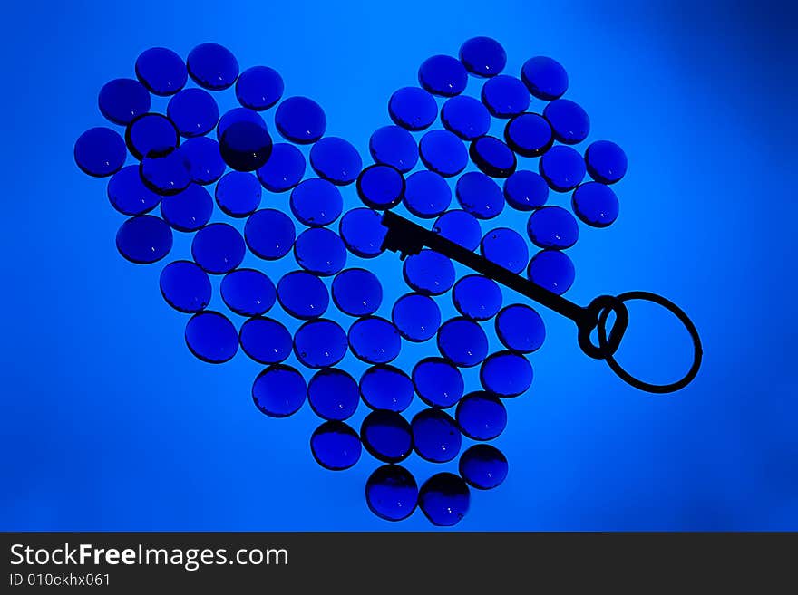 Heart shape from shiny glass pebbles with key inside