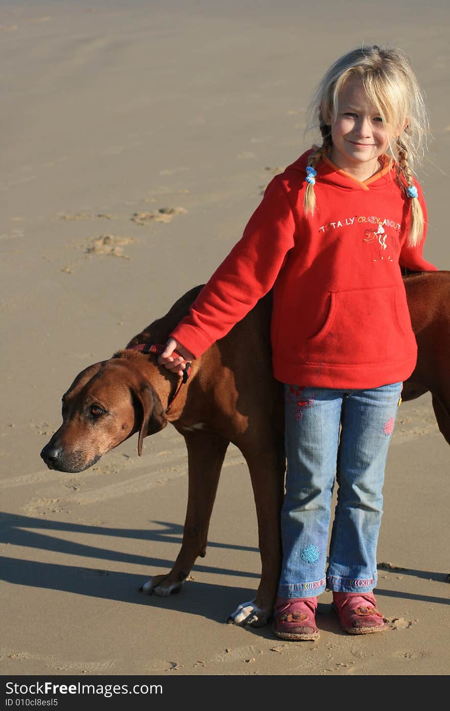 A beautiful white caucasian girl child with her dog on the beach. A beautiful white caucasian girl child with her dog on the beach