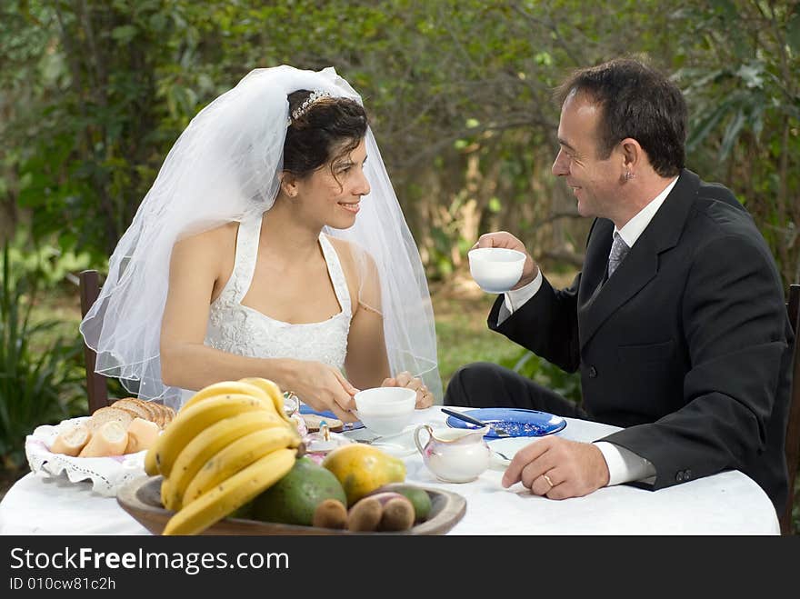 A newly married couple, sitting at a table smiling and gazing at each other - horizontally framed. A newly married couple, sitting at a table smiling and gazing at each other - horizontally framed