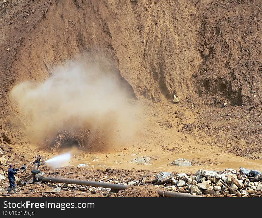 The man washes away ground for production of gold. The man washes away ground for production of gold