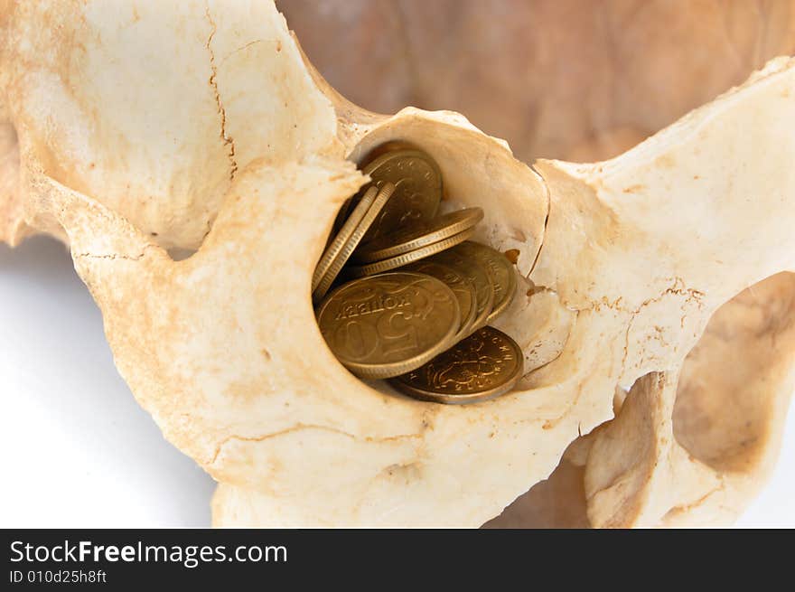 Old broken skull against white background with gold coins in eye socket. Old broken skull against white background with gold coins in eye socket