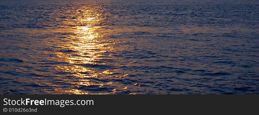 Ocean's sunset with gold sunbeam over water