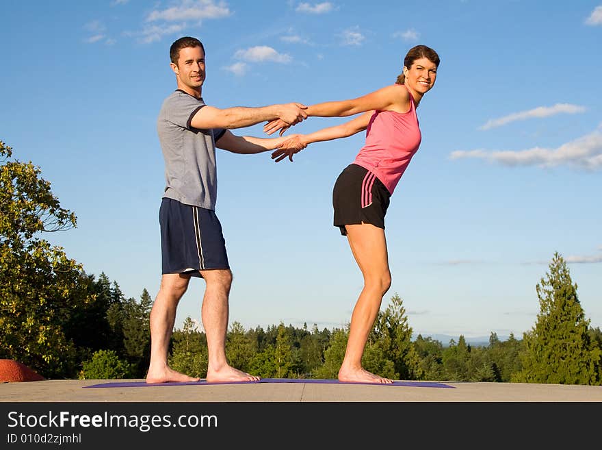 A woman, gets her arms stretched behind her back by a man, smiling. - horizontally framed. A woman, gets her arms stretched behind her back by a man, smiling. - horizontally framed