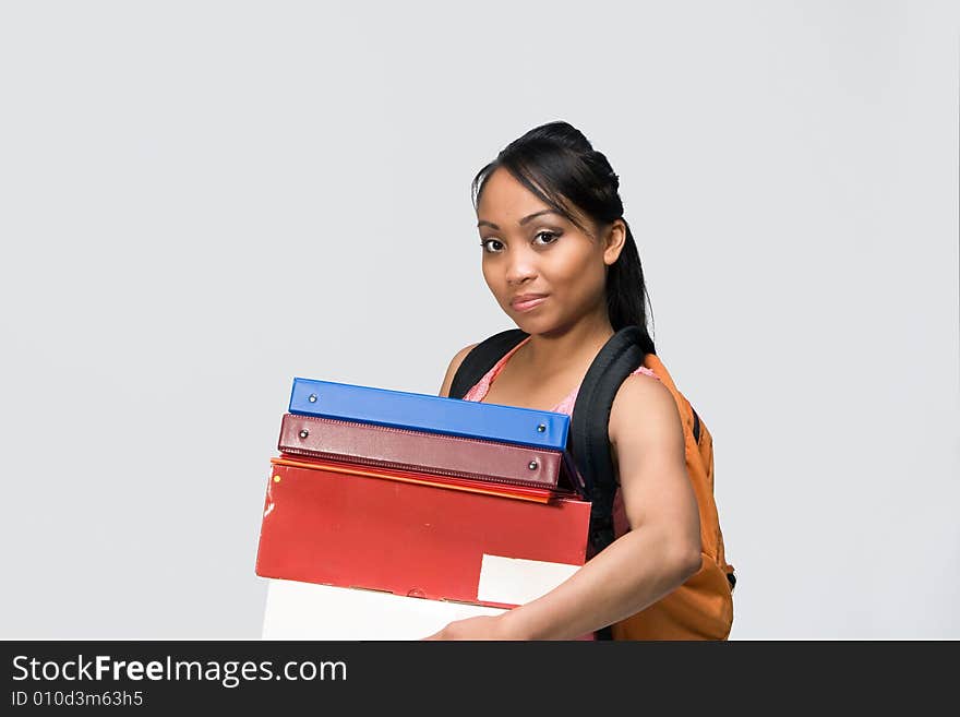 Female student wearing a backpack carries  notebooks and papers. Horizontally framed photograph. Female student wearing a backpack carries  notebooks and papers. Horizontally framed photograph.