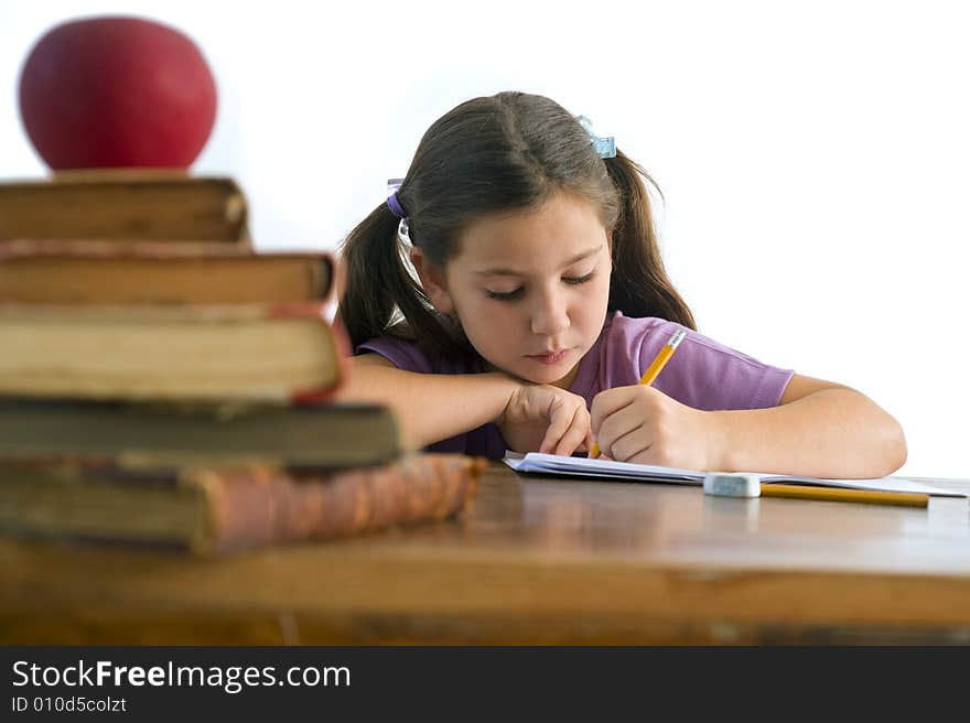 Girl pupil sitting by the table with globe and red apple on a pile of books, Isolated on white
