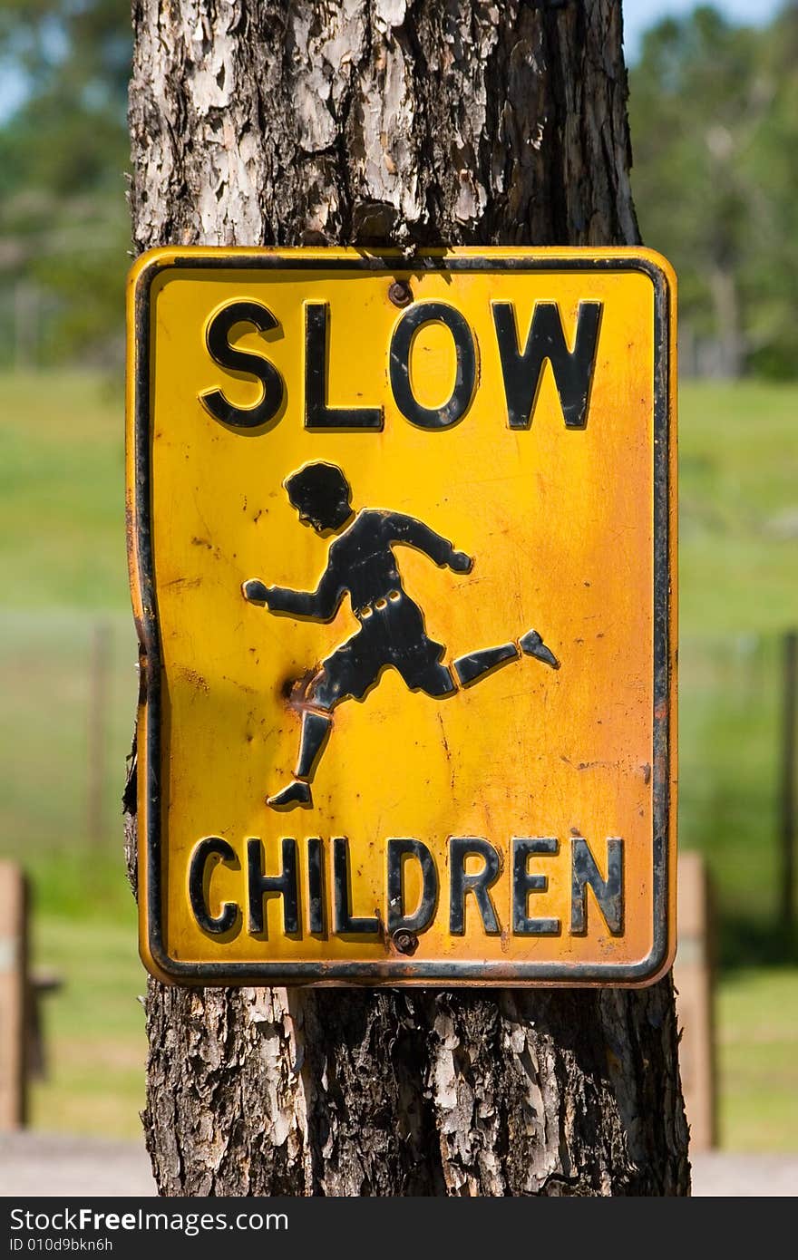 Old fashioned Slow Children street sign attached to a tree