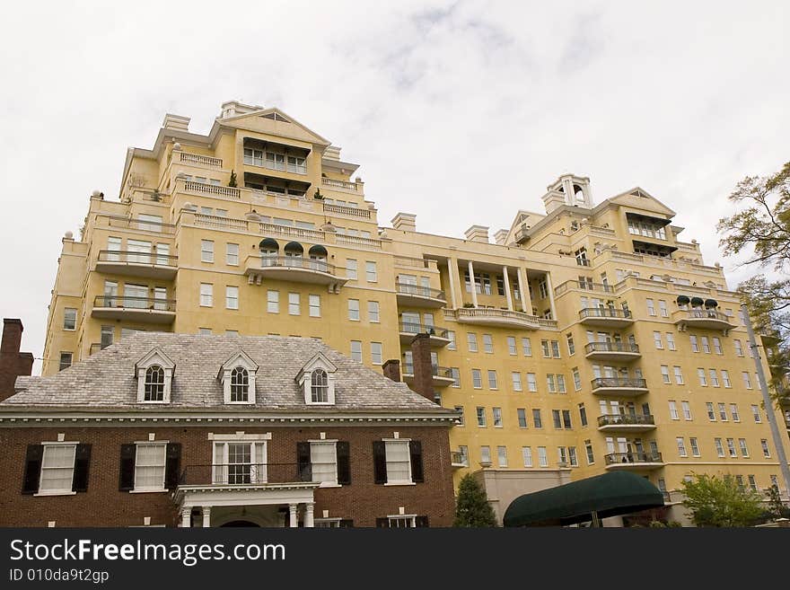 An old brick house in front of a modern yellow stucco condominium complex. An old brick house in front of a modern yellow stucco condominium complex