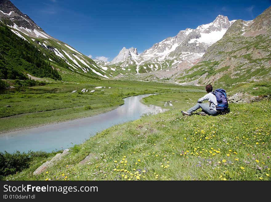 Male hiker enjoying the view over the beautiful landscape of Lac Combal, Val Veny, Courmayeur, Italy. Male hiker enjoying the view over the beautiful landscape of Lac Combal, Val Veny, Courmayeur, Italy