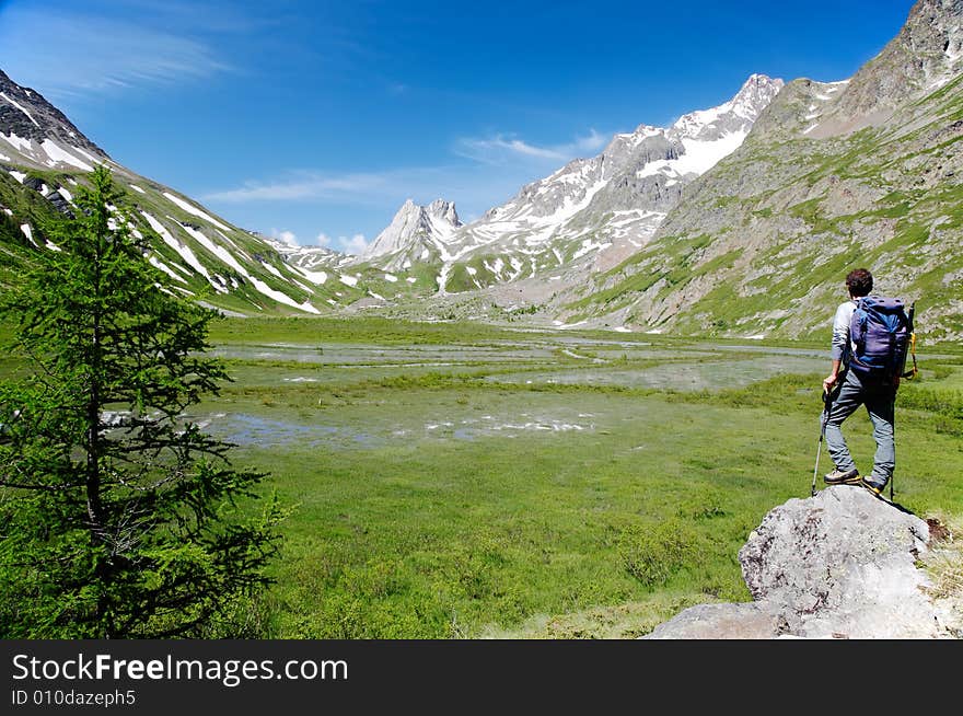 Male hiker enjoying the view over the beautiful landscape of Lac Combal, Val Veny, Courmayeur, Italy. Male hiker enjoying the view over the beautiful landscape of Lac Combal, Val Veny, Courmayeur, Italy