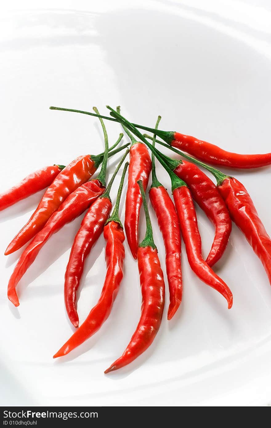 Bold chili cayenne peppers on shiny white plate. Bold chili cayenne peppers on shiny white plate