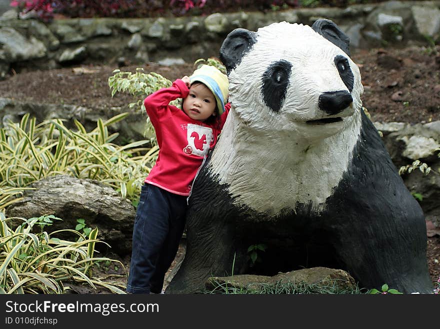 Asian little girl standing with panda statue.