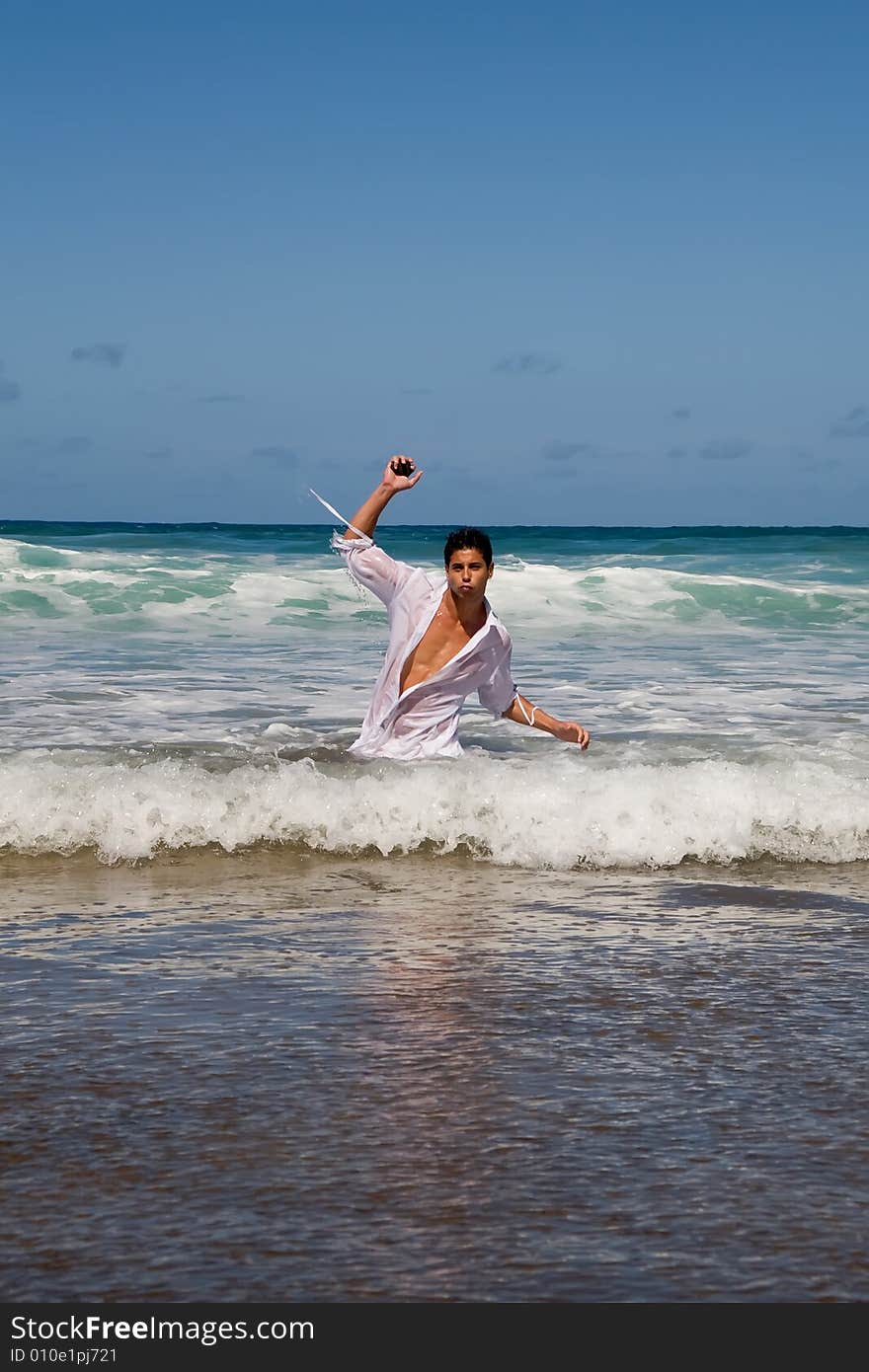 Young athelitc man posing on the sea shore on blue day. Young athelitc man posing on the sea shore on blue day