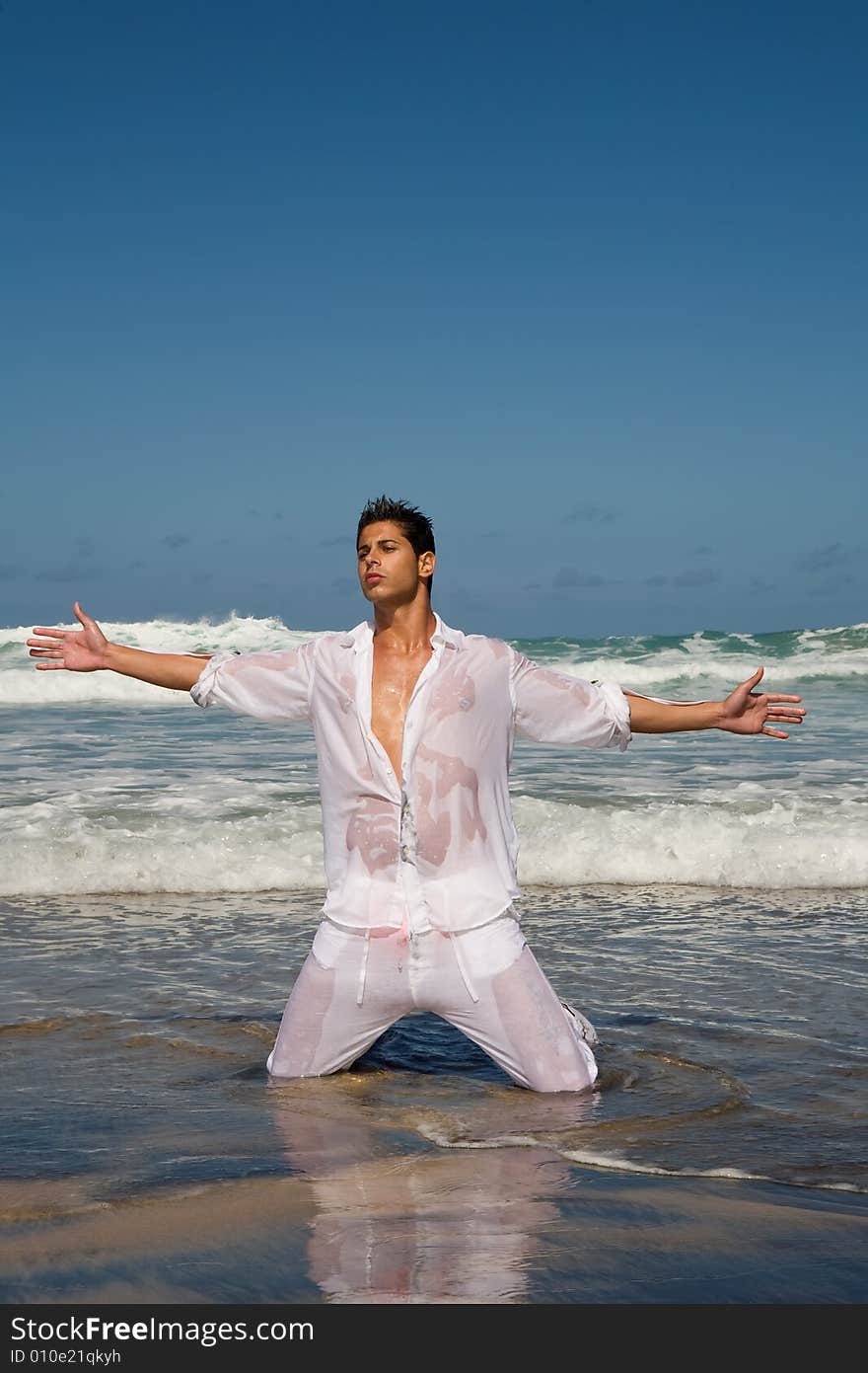 Young athelitc man posing on the sea shore on blue day. Young athelitc man posing on the sea shore on blue day