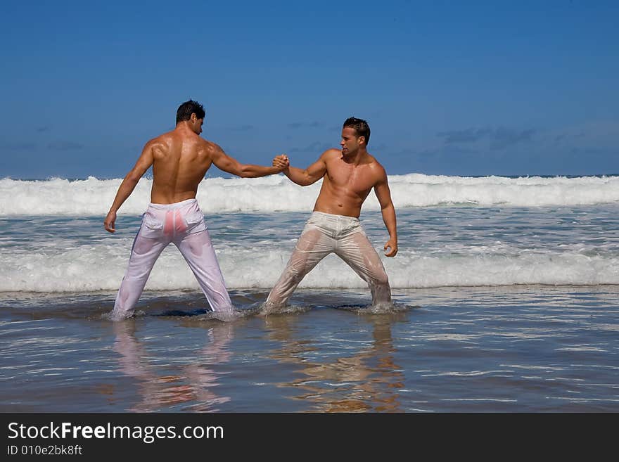 Two young man play at sea shore on blue day. Two young man play at sea shore on blue day