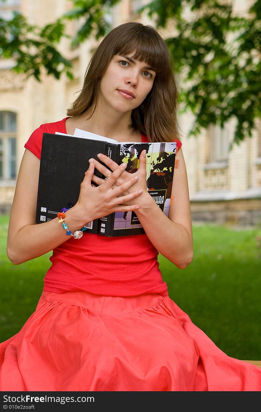 A beautiful young college girl holding a book. A beautiful young college girl holding a book