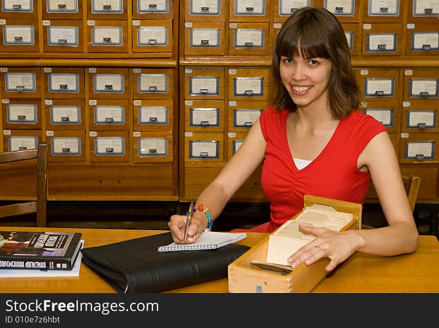 A beautiful young college girl working with a cardfile drawer. A beautiful young college girl working with a cardfile drawer