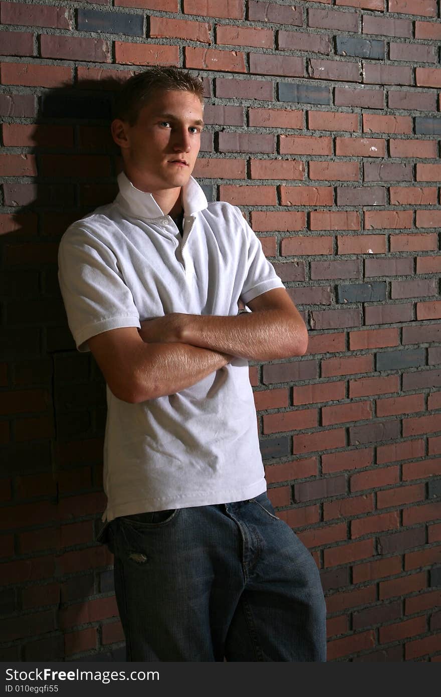 Muscular man standing next to a brick wall