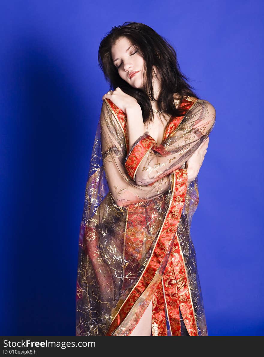 Beautiful young woman embracing herself wearing a partially see-through oriental style robe.