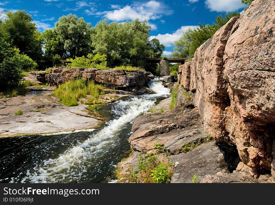 River stream with rocks and bridge