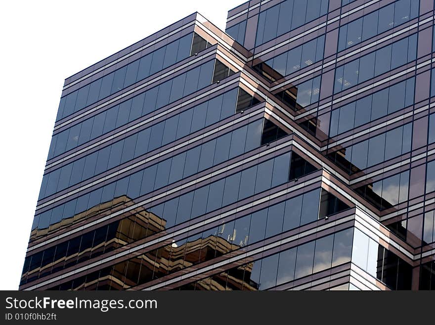 A glass modern building reflecting the sky and other buildings isolated on white. A glass modern building reflecting the sky and other buildings isolated on white