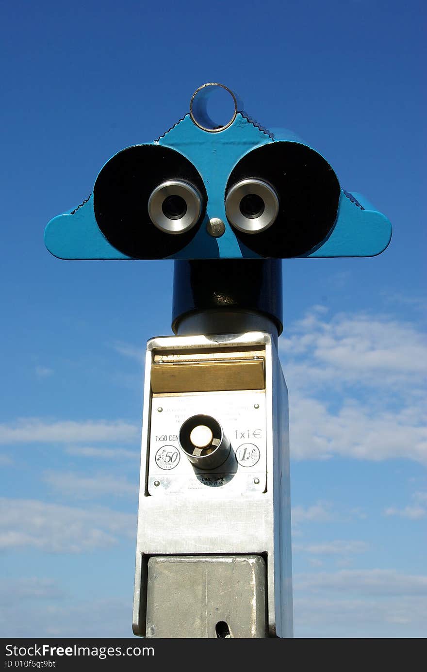 Coin-operated tourist binoculars over blue sky. Coin-operated tourist binoculars over blue sky