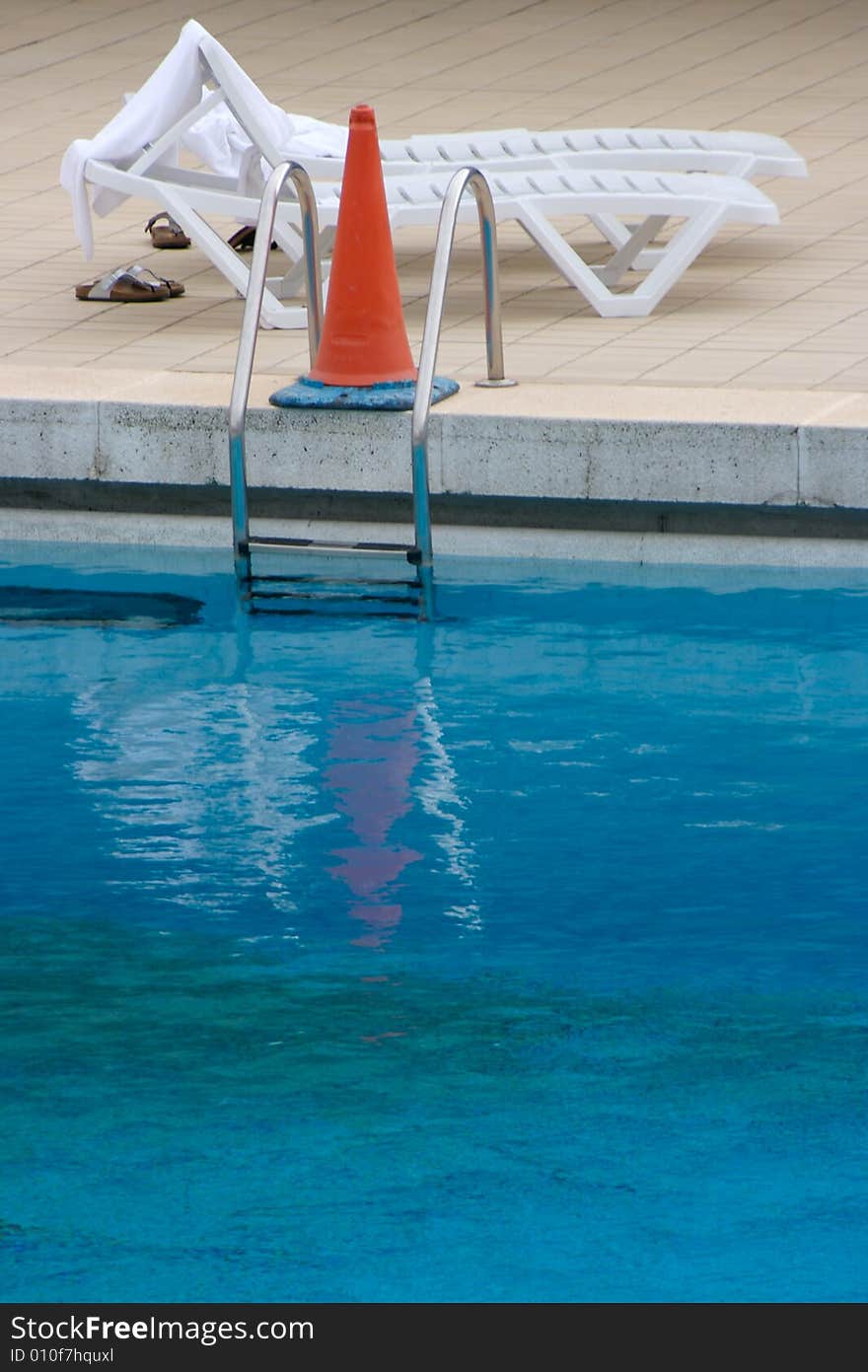 Abandoned beach chair next to a closed pool. Abandoned beach chair next to a closed pool.