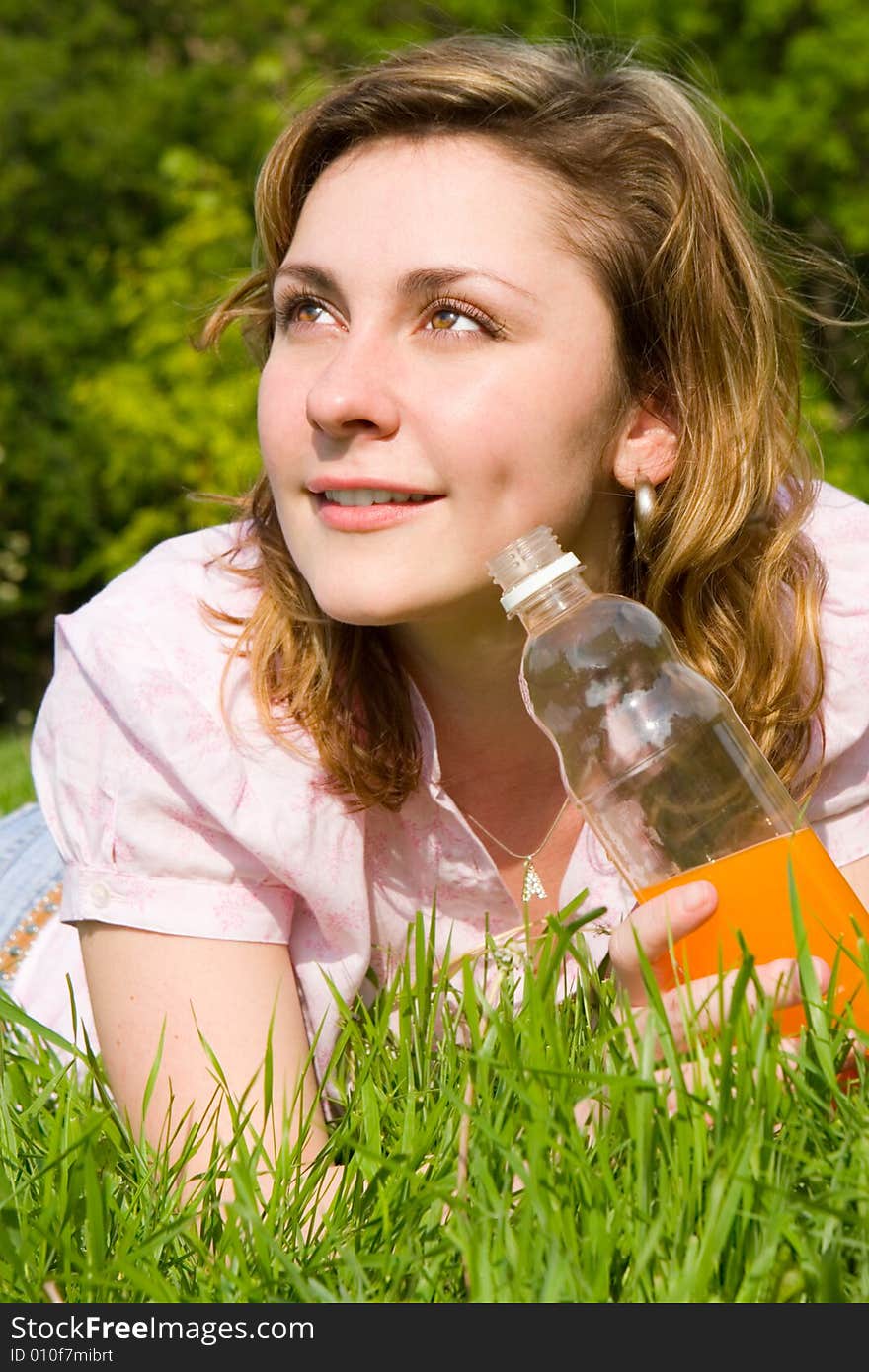 Woman drinking juice on green grass