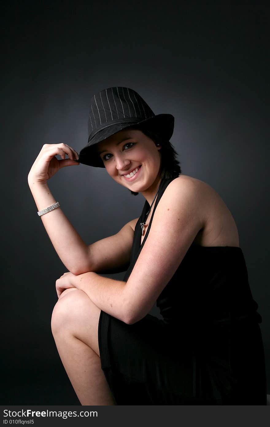 Pretty teenage girl in black top hat, dress, and bare arms and legs. Pretty teenage girl in black top hat, dress, and bare arms and legs