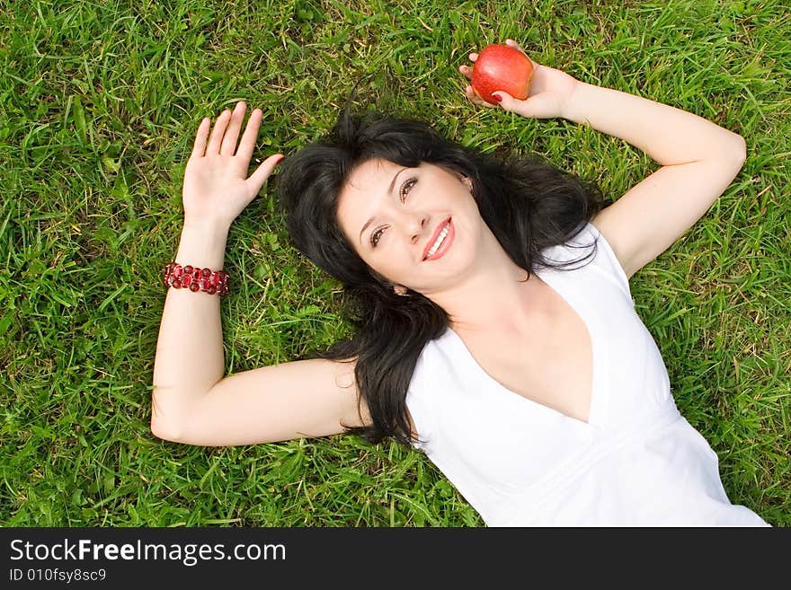 Pretty woman eating green apple on the summer glade