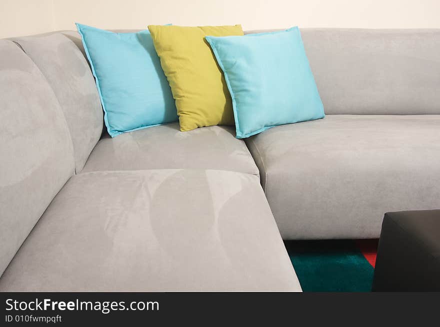 Grey Suede Couch Corner Area with colorful rug and pillows.